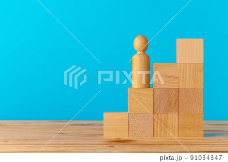 Stacked wooden blocks on wooden desk against blue background Stacked wooden blocks on wooden desk against blue background 91034347