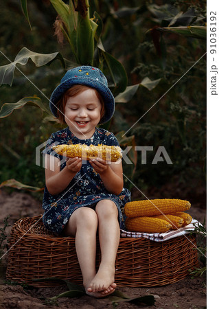Happy little girl holding an ear of corn. 91036192