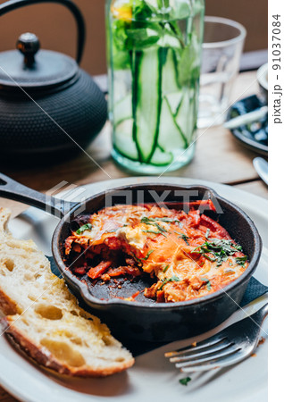Shakshuka in iron pan served with bread Shakshuka in iron pan served with bread 91037084