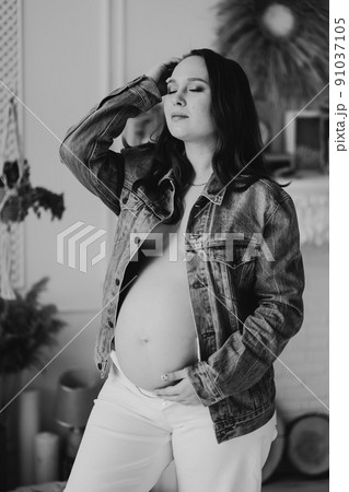 black and white. a beautiful pregnant woman in a denim jacket with a naked tummy 91037105