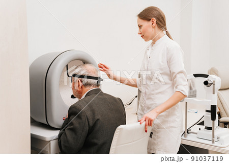 oculist examination of elderly man on device perimeter of field of view 91037119