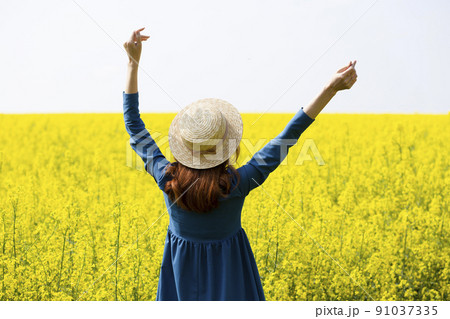 girl walking in a field of yellow rapeseed 91037335