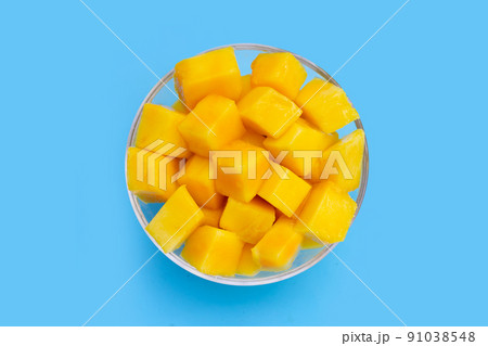 Yellow mango cube slices on blue background. 91038548