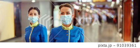 Stewardesses in medical masks carrying travel bags at airport Stewardesses in medical masks carrying travel bags at airport 91039361