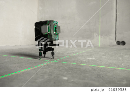 Laser level, construction, finishing work in the room. Laser building level with green beams on the wall bare cement of the house Laser level, construction, finishing work in the room. Laser building level with green beams on the wall bare cement of the house 91039583