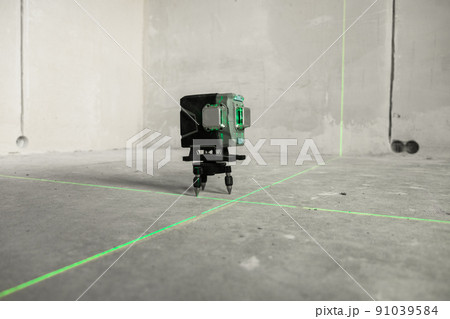 Laser level, construction, finishing work in the room. Laser building level with green beams on the wall bare cement of the house Laser level, construction, finishing work in the room. Laser building level with green beams on the wall bare cement of the house 91039584