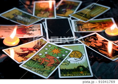 Tarot reading with tarot card background and candlelight on the table for Astrology Occult Magic Spiritual Horoscopes and Palm reading fortune teller tarot reader Tarot reading with tarot card background and candlelight on the table for Astrology Occult Magic Spiritual Horoscopes and Palm reading fortune teller tarot reader 91041769