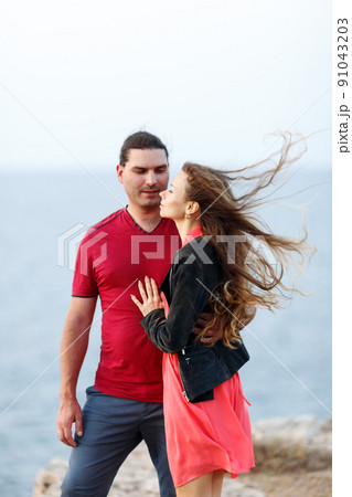 Portrait of lovely middle-aged couple looking aside at copyspace and hugging while standing at the seaside rock cliff edge. Portrait of lovely middle-aged couple looking aside at copyspace and hugging while standing at the seaside rock cliff edge. 91043203