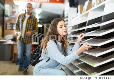 Woman chooses laminate flooring in store 91044331