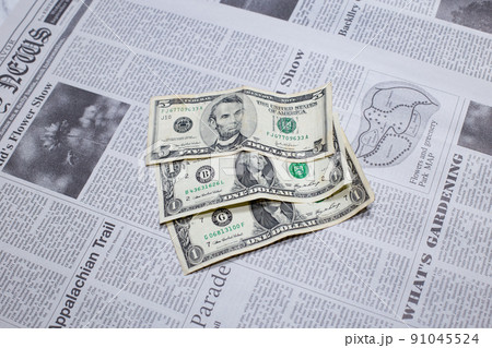 英字新聞に置かれた米国の1ドル紙幣と5ドル紙幣 91045524