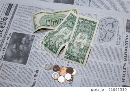 英字新聞に置かれた米国の1ドル紙幣と5ドル紙幣とコイン 91045530