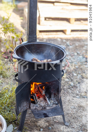Cooking food or pilaf in a cauldron on fire. Cooking in cauldron on open fire in nature. Bowler on bonfire in forest. Close-up fire flame. Copy space. 91045964
