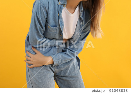 Girl with abdominal pain on yellow background Girl with abdominal pain on yellow background 91048838