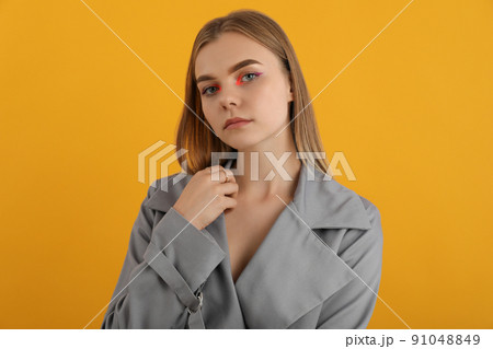 Beautiful model girl in autumn cloak on yellow background 91048849