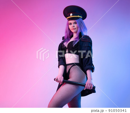 Sexy girl in police uniform posing in underwear with a police rubber baton in neon light Sexy girl in police uniform posing in underwear with a police rubber baton in neon light 91050341