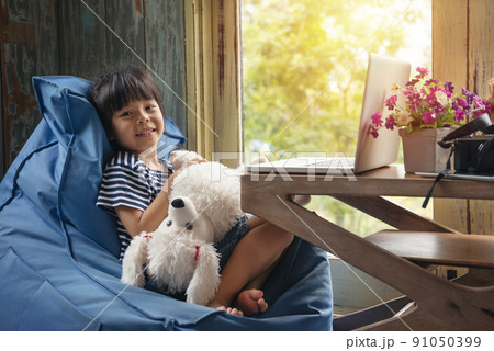 Cute Little asian Girl Sitting use Laptop at the Desk in the Living Room Cute Little asian Girl Sitting use Laptop at the Desk in the Living Room 91050399