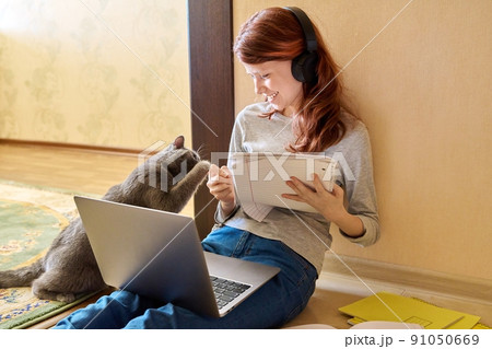Preteen girl studying at home using laptop along with cat Preteen girl studying at home using laptop along with cat 91050669