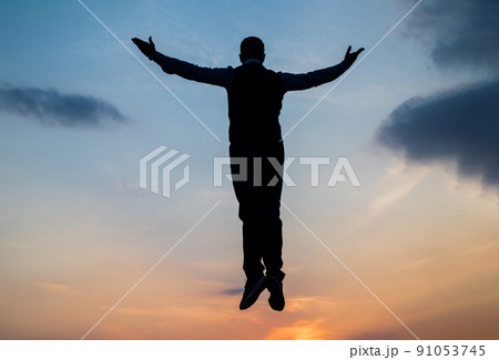 silhouette of man float in sunrise sky with raised hands, freedom 91053745