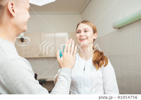 Beautiful female dentist in office in clinic, satisfied happy client shakes hands, excellent professional service. Clap 91054756