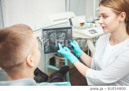 woman doctor shows patient his x-ray of teeth and explains problems. Gloves woman doctor shows patient his x-ray of teeth and explains problems. Gloves 91054800
