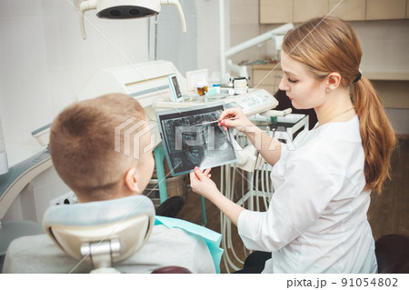 woman doctor shows patient his x-ray of teeth and explains problems. 91054802