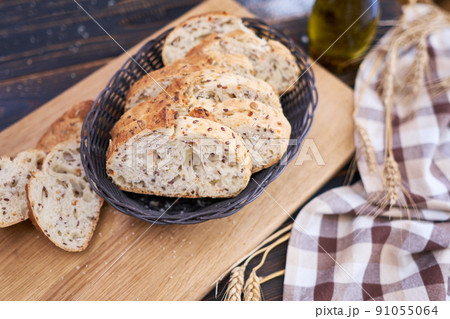 Fresh sliced bread on wooden cutting board at kitchen table 91055064