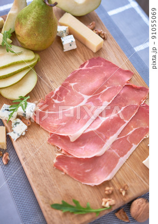 Jamon or prosciutto ham slices, Blue cheese, pears and walnuts on wooden board 91055069