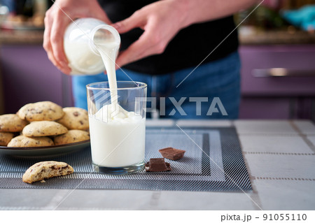 Pouring milk in glass with Homemade chocolate cookies on background 91055110