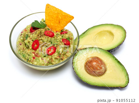 Healthy vegetarian organic guacamole Mexican dip sauce served in glass bowl with nachos or tortilla chips isolated on white background 91055112