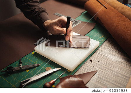 leatherworker punches holes. Tanner works with leather, small business, production. 91055983