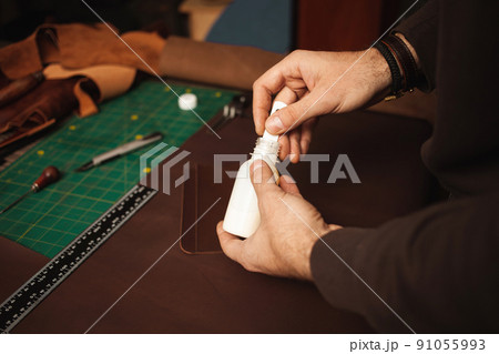 leatherworker use glue. Tanner works with leather, small business, production. Closeup 91055993