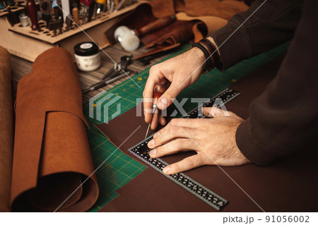 leatherworker draws, measures with ruler. Tanner works with leather, small business, production. leatherworker draws, measures with ruler. Tanner works with leather, small business, production. 91056002