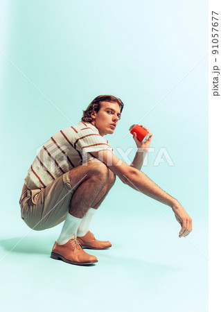 Portrait of young man in retro style outfit, drinking coke, posing isolated over light blue studio background. Resting Portrait of young man in retro style outfit, drinking coke, posing isolated over light blue studio background. Resting 91057677