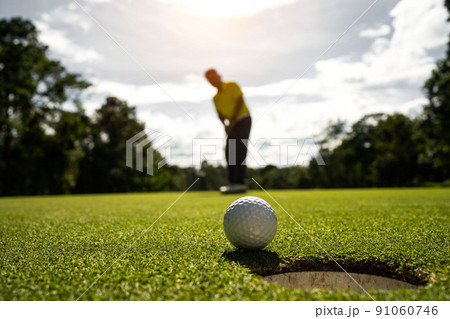 Golfer putting ball on the green golf, lens flare on sun set evening time. Golfer putting ball on the green golf, lens flare on sun set evening time. 91060746