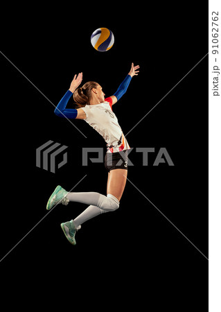 Dynamic portrait of professional volleyball player in sports uniform playing volleyball isolated on dark background. Sport, healthy lifestyle, team, action, motion concept Dynamic portrait of professional volleyball player in sports uniform playing volleyball isolated on dark background. Sport, healthy lifestyle, team, action, motion concept 91062762