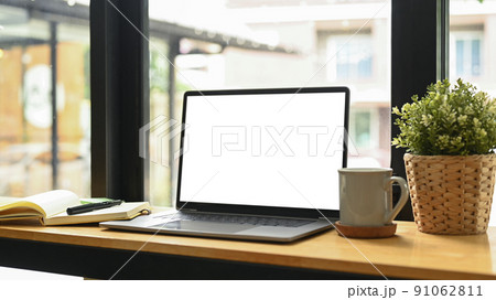 Computer laptop with blank display, potted plat, coffee cup and notebook on wooden table Computer laptop with blank display, potted plat, coffee cup and notebook on wooden table 91062811