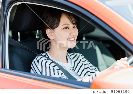 笑顔で車の運転をする若い女性 91063196