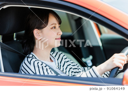 笑顔で車の運転をする若い女性 91064149