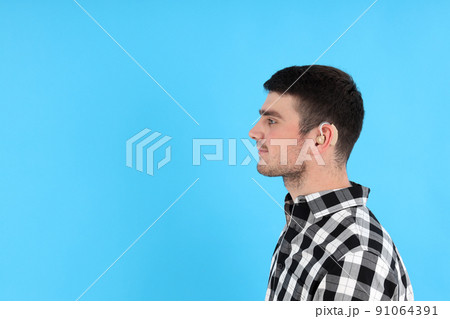Young man with hearing aid on blue background Young man with hearing aid on blue background 91064391