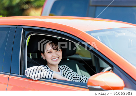 笑顔で車の運転をする若い女性 91065903