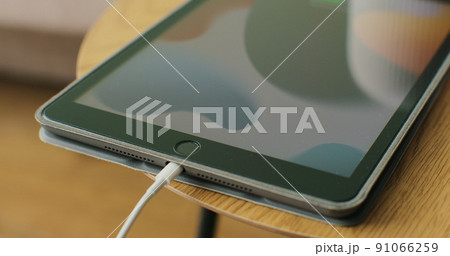 Woman hand plugging charging cable into pc digital tablet. Close up shot. 91066259