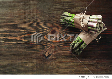 An edible, raw stems of asparagus on a wooden background. An edible, raw stems of asparagus on a wooden background. 91066260
