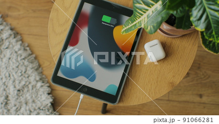 Top view. Woman hands plugging the charging cable in the port of a tablet device to charge the battery. Top view. Woman hands plugging the charging cable in the port of a tablet device to charge the battery. 91066281