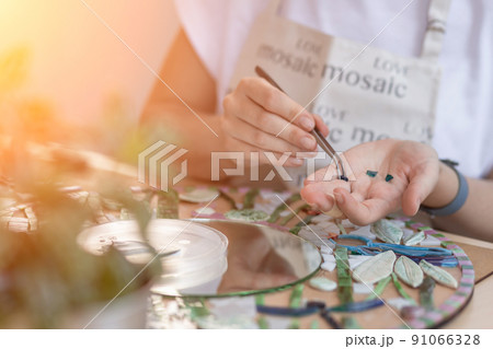 Hands of master working on new modern colorful mosaic. Close-up 91066328