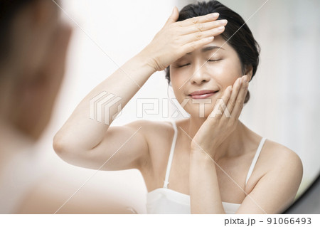 鏡に向かってスキンケアをするアラフィフの女性 91066493
