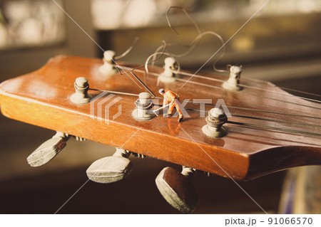 The technician worker figure fixing old guitar strings. The technician worker figure fixing old guitar strings. 91066570