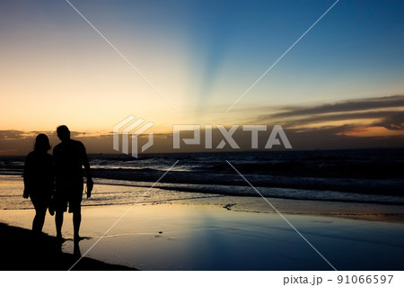 romantic couple silhouette on sunset with colors reflecting in the sky and the sea romantic couple silhouette on sunset with colors reflecting in the sky and the sea 91066597