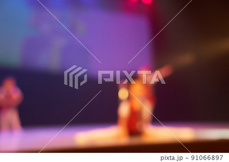 Silhouettes of small dancers with elements of gymnastic dance. Colored blurred background of the dance festival. Bright stage lighting. High quality photo 91066897