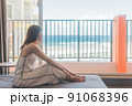 沖縄に一人旅をする女子がホテルで海を眺める 91068396