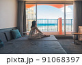 沖縄に一人旅をする女子がホテルで海を眺める 91068397